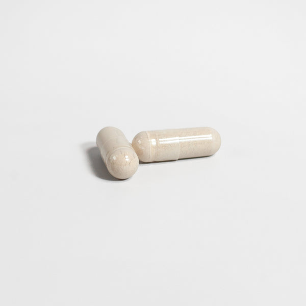 Two beige capsules of men's vitality and wellness pills from RevitaGenix Labs on white background